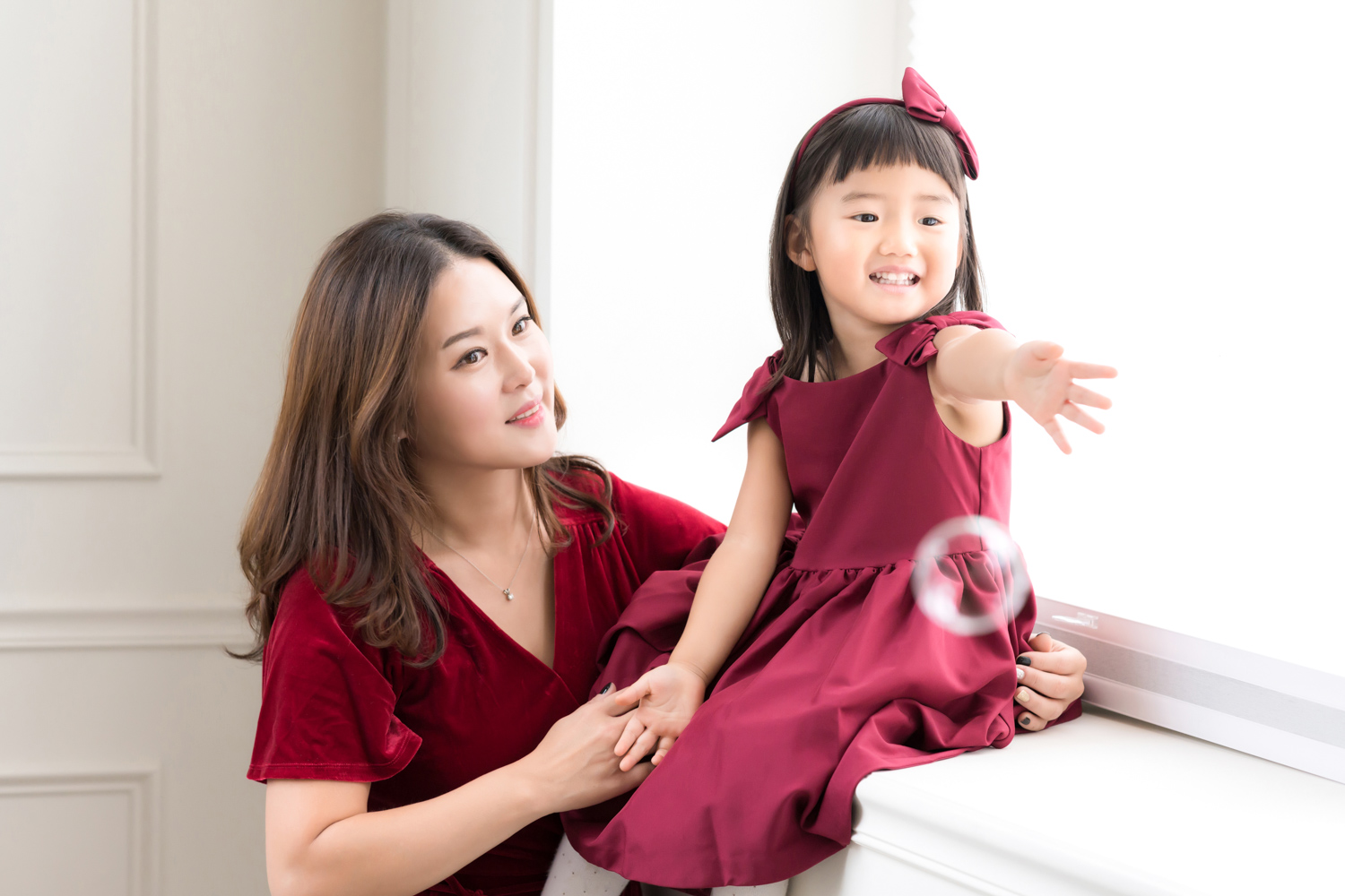 Hyorin reaches for her dad while she sits with her mom during a photoshoot.