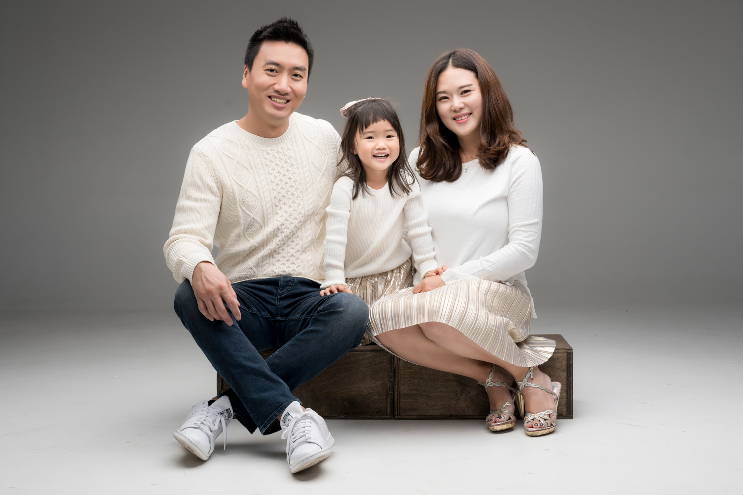 Hyorin sits with her parents in matching cream colored outfits.