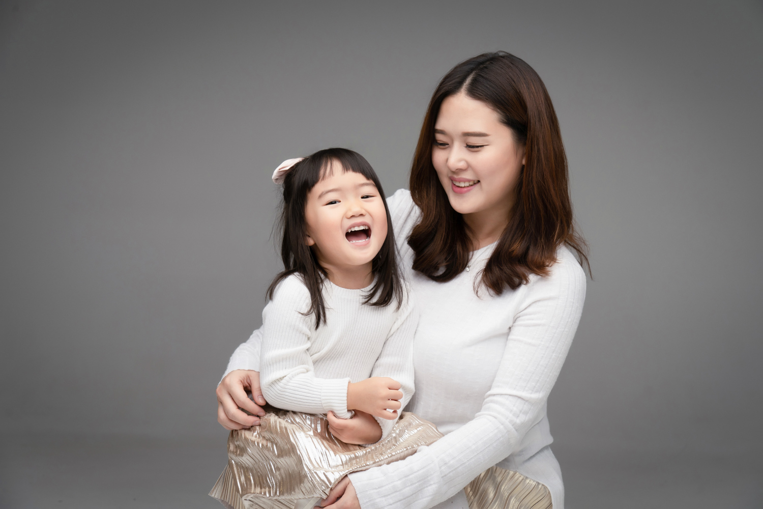 Daughter laughs with mom during a mother daughter photoshoot.