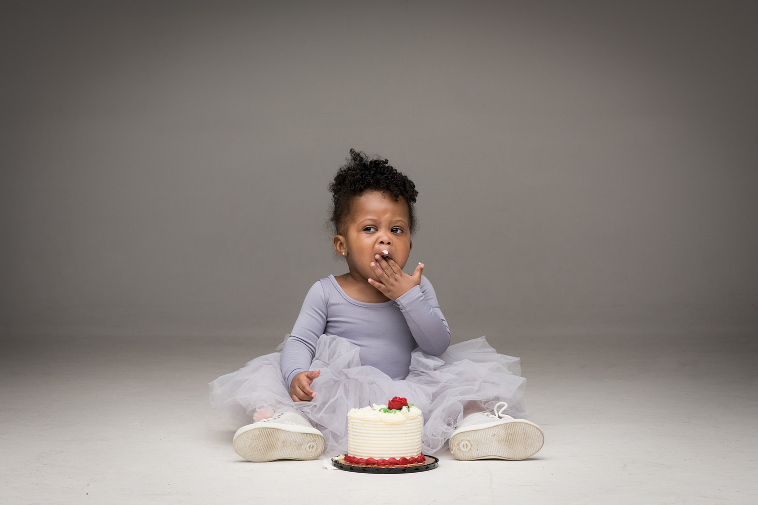 A Chicago toddler digs into a mini birthday cake in a grey tutu.