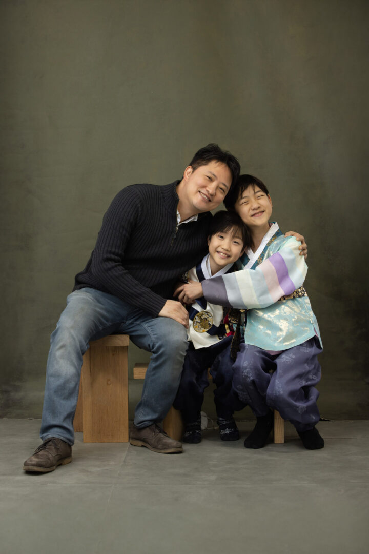 Soohyun Kim, founder of gugwa, smiling with his two children dressed in traditional Korean hanbok, capturing a heartfelt family moment.